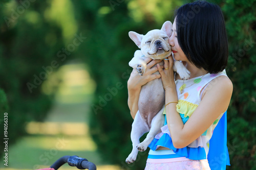 A woman kisses small pet a French Bulldog puppy. with copy space.