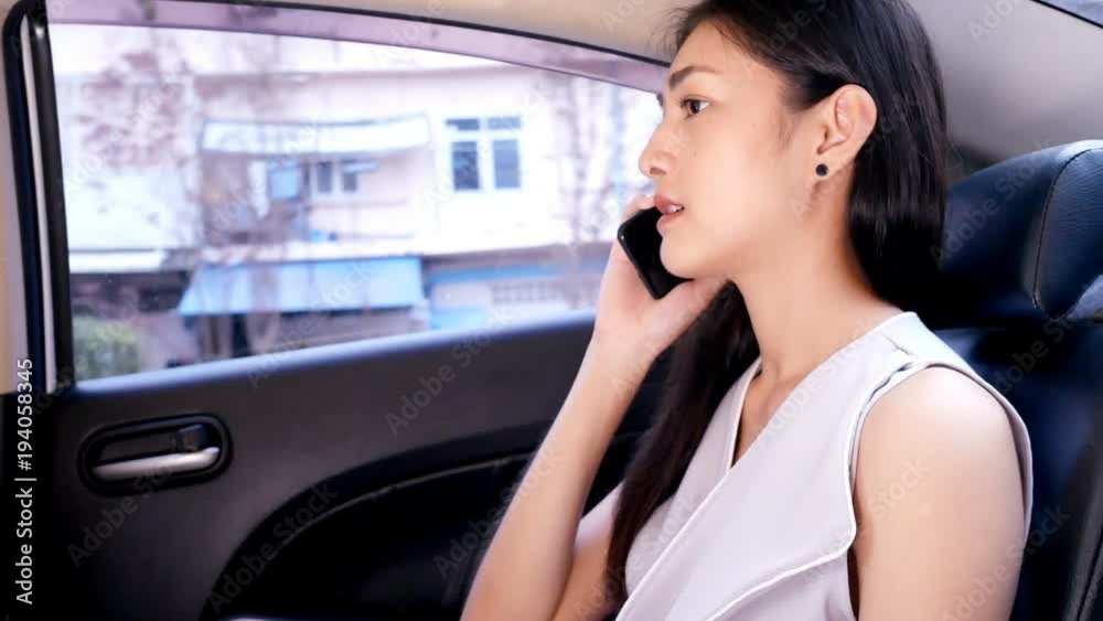 Asian woman using smartphone inside car. 