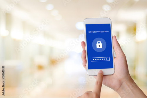 Hand using smart phone with password login on screen over blur background, cyber security concept