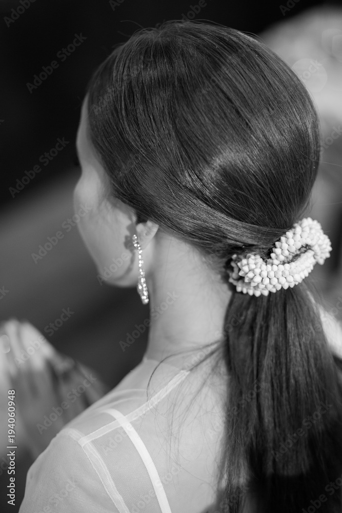 Back view of unrecognizable young woman with decorate hair in white wedding dress.