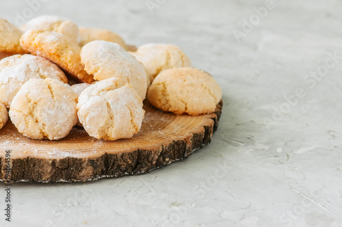 Homemade amaretti cookies on a wooden board on a white stone backdrop.