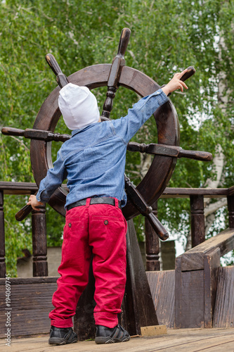 the boy holds a wooden ship's wheel