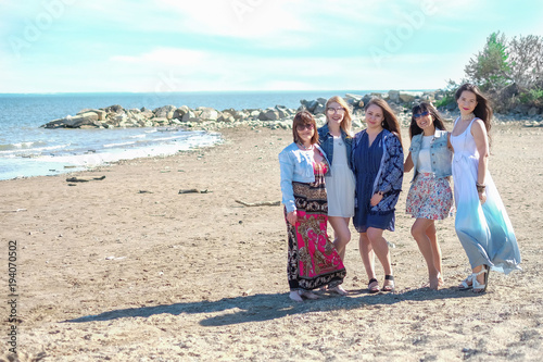 summer holidays concept - group of smiling young women is resting on the seashore