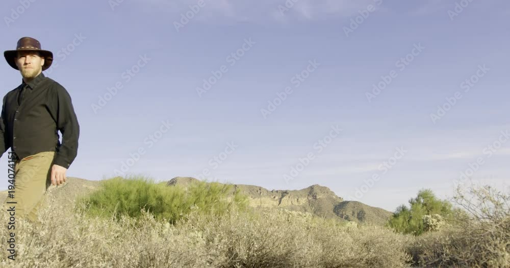 Cowboy walking out of frame with desert background Cowboy walking out of frame with desert background