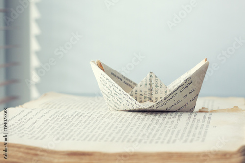a paper ship is sent to the path of knowledge and words on sea book background