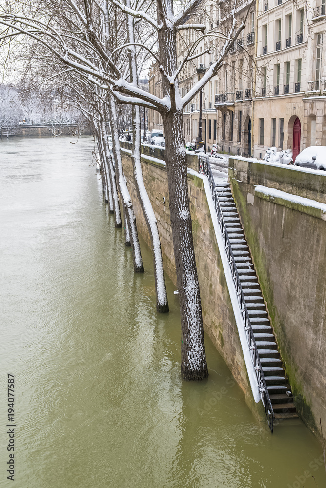 Paris under the snow and floods, staircase on the Seine, beautiful building facades in winter 
