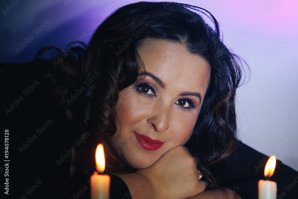 Portrait of adult girl with black hair and candles in the dark room Portrait of adult girl with black hair and candles in the dark room