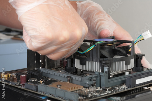 Close up of man hands installing CPU cooler fan on new, modern  motherboard
