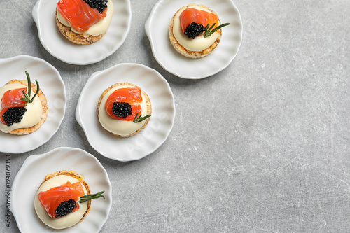 Billede på lærred Tasty appetizer with black caviar and salmon on plates