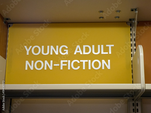Young adult, non-fiction sign top of library shelf