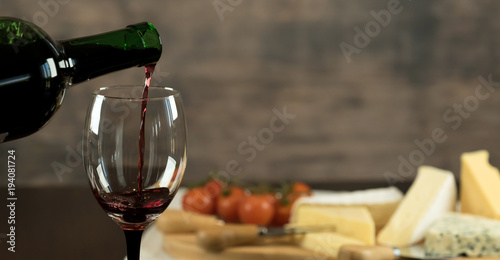 Fototapeta Naklejka Na Ścianę i Meble -  Red wine poured into a glass  with cheese board 