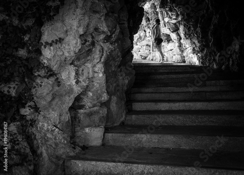 Female walks by the stairs in the rock cave in Villetta Di Negro park in Genoa, Italy.