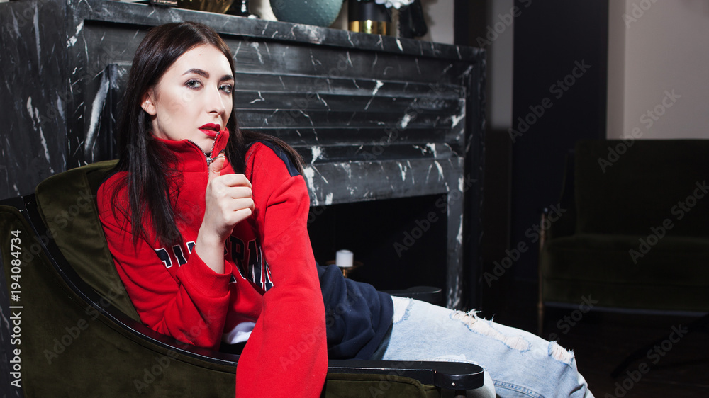 Trendy young woman ia a red hoodies. Portrait in fashionable interior. Trendy young woman ia a red hoodies. Portrait in fashionable interior.