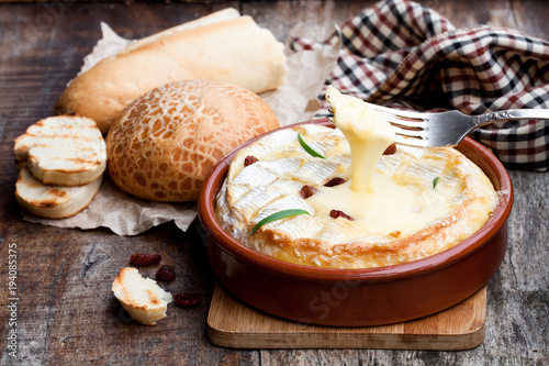 Delicious  hot baked camembert with sultanas on wooden table photo