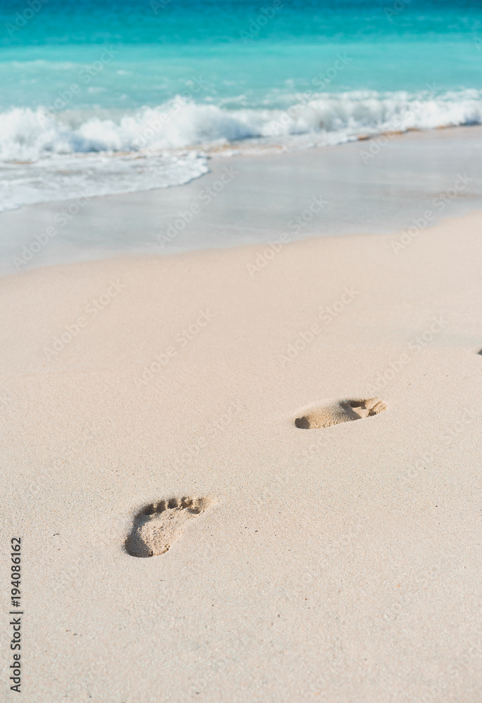 Azure ocean waves rolling on the beach with foot prints Azure ocean waves rolling on the beach with foot prints