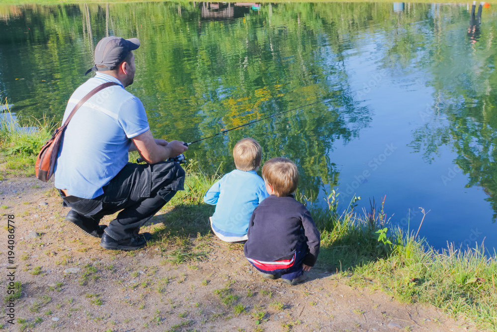 Dad and children are fishing. Dad and two sons are fishing.