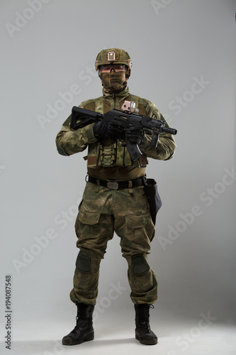 Full-length portrait of soldier in camouflage with gun