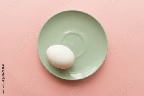 One white egg on pink pastel background. minimal concept. top view