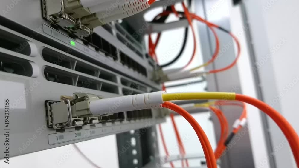 Fiber optic patch cords plugged into a network switch or router with blinking green led lights. Conceptual footage for data connection.