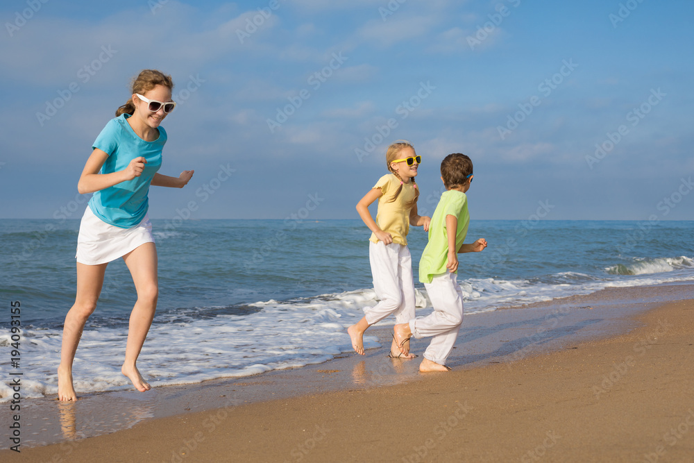 Three happy children running on the beach at the day time.