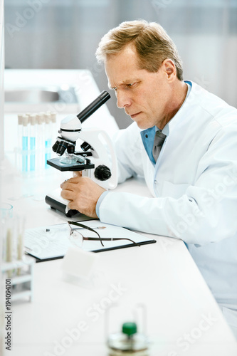 Clinical Test. Scientist With Microscope In Laboratory.