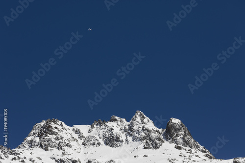 Snow-covered, fresh white mountain peak with a plane in the Alps of Switzerland