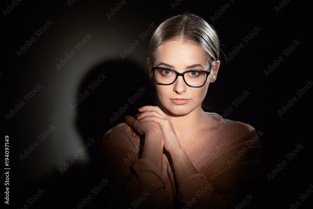 girl in glasses in studio on a dark background. light spots. girl in glasses in studio on a dark background. light spots.