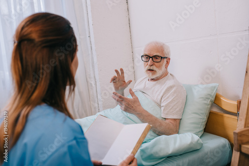 Old man patient and nurse discussing plot of the book