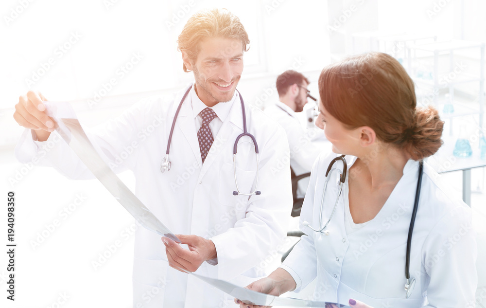 Male surgeon with nurse examining x-ray report Male surgeon with nurse examining x-ray report