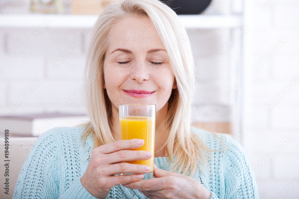 Woman drinking orange juice smiling. Beautiful middle aged Caucasian model face closeup. Woman drinking orange juice smiling. Beautiful middle aged Caucasian model face closeup.