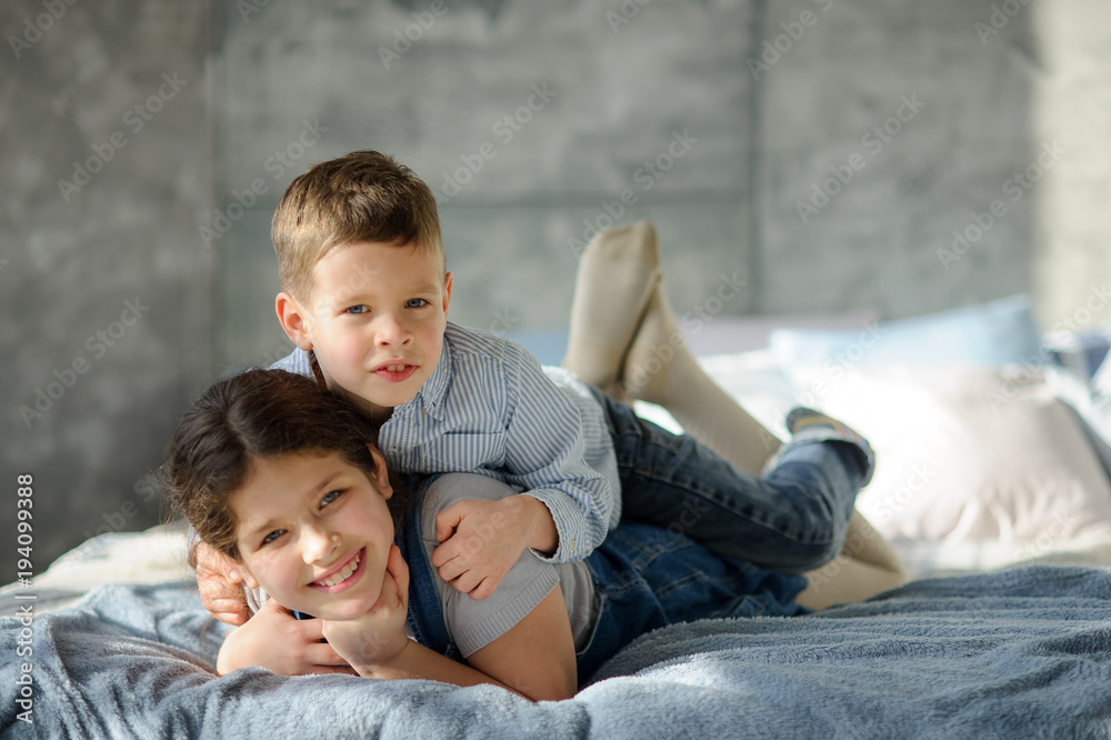 Fototapeta premium Two children, the boy and the girl, lie on a bed.