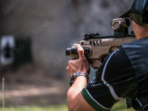 Male aim and shoot submachine gun to target in shooting competition photo