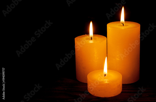 Three candles with flame at night with copy space on black background