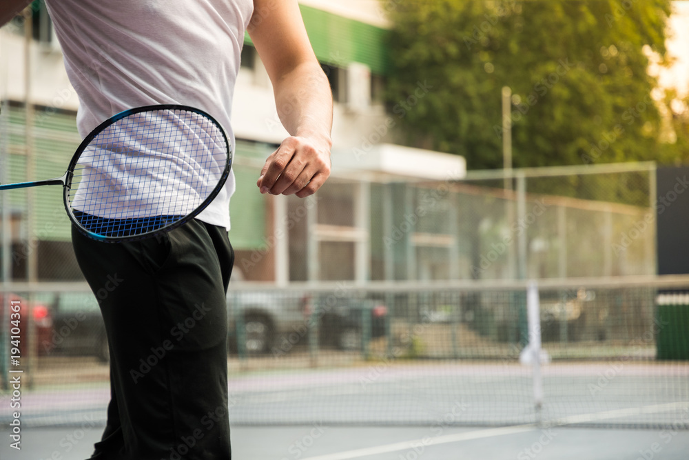 Badminton player in sport outfit is warm up before playing the game at  outdoor hard court. Building background Stock Photo | Adobe Stock