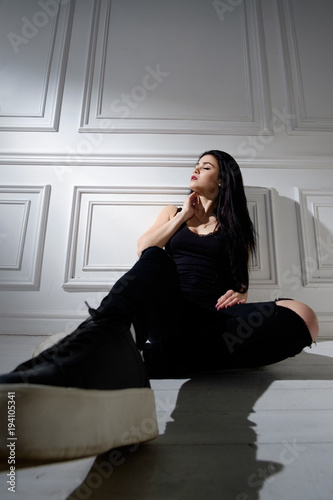 brunette caucasian girl in black casual style clothes sitting in white interior