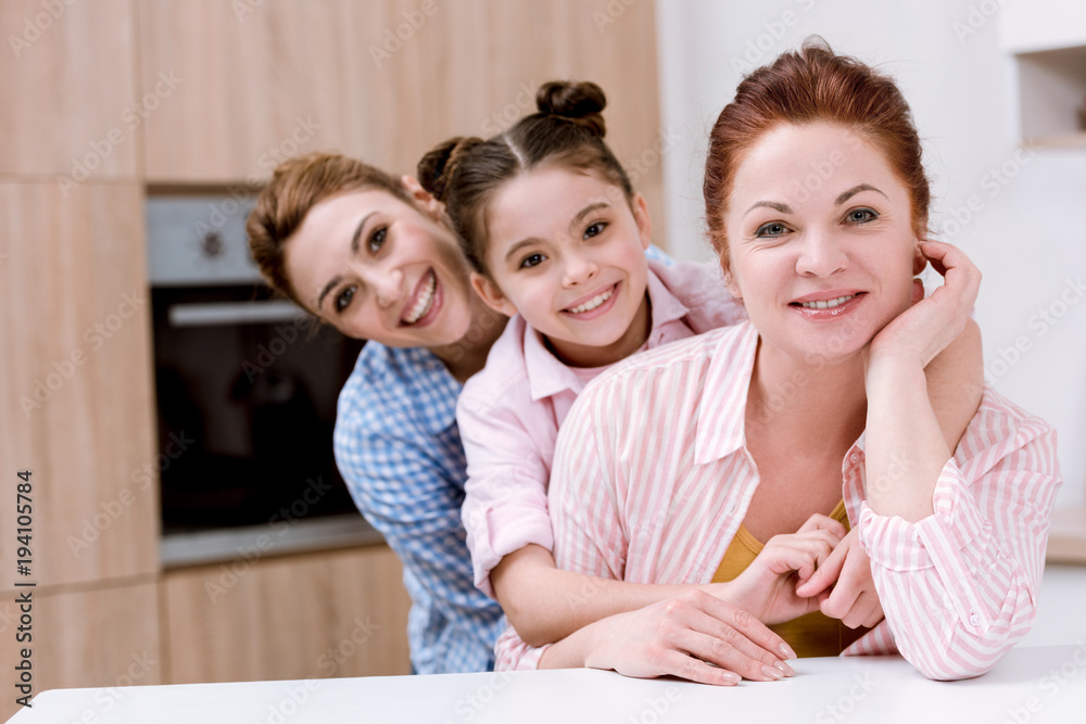 three generations of happy beautiful women standing in row together at kitchen and looking at camera three generations of happy beautiful women standing in row together at kitchen and looking at camera