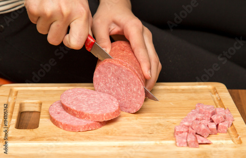 Slicing sausage with a knife on the board