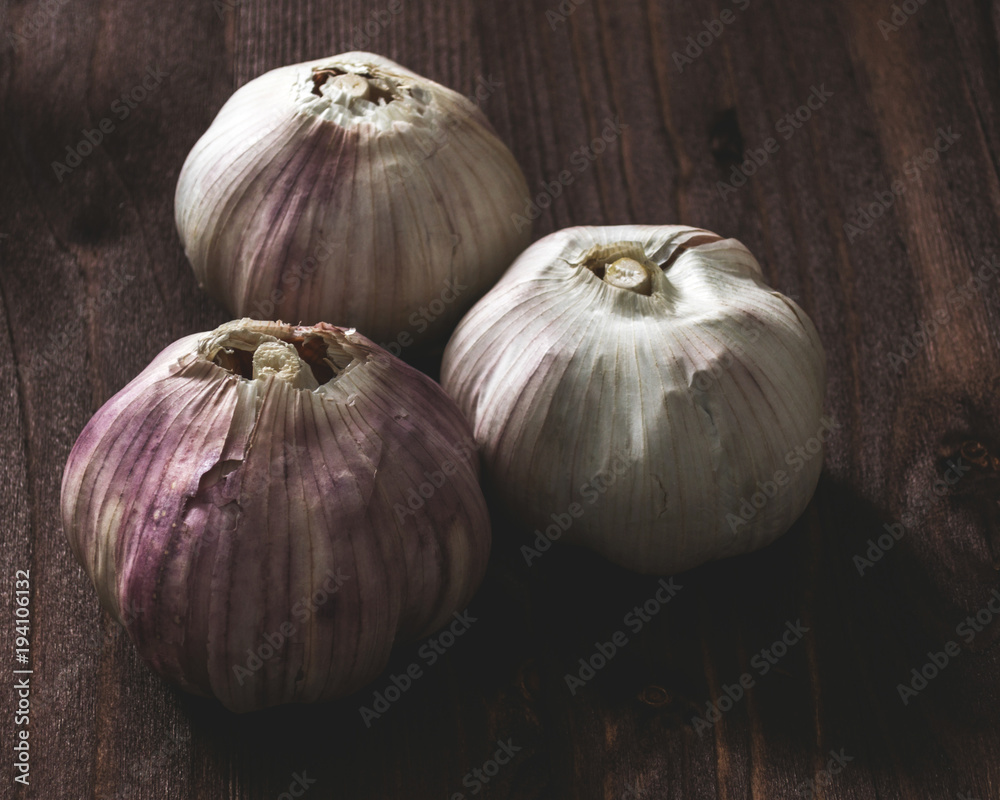 Obraz premium Three heads of garlic on wooden background