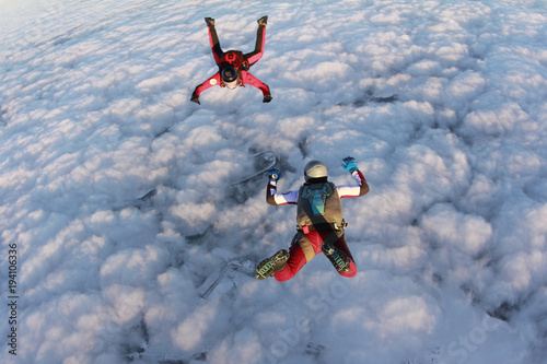 Two skydivers are in the winter sunset sky.