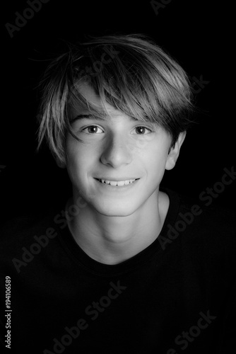 young blonde smiling guy portrait on black background - black and white photo