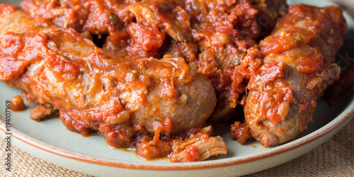 Sausages and pork pullet cooked in traditional Italian tomato ragu sauce. Dish on burlap. Banner