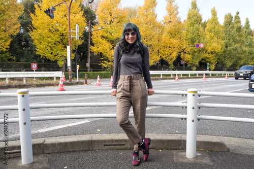 A trendy female traveller posing on the famous Genko Avenue with beautiful trees that have turned yellow in the autumn season in Meiji Jingu Gaien Park
