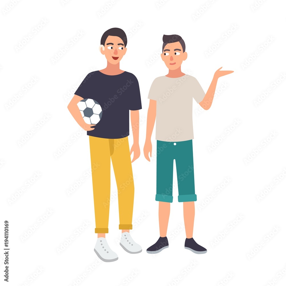 Smiling boy with hearing impairment holding soccer ball and standing together with his friend