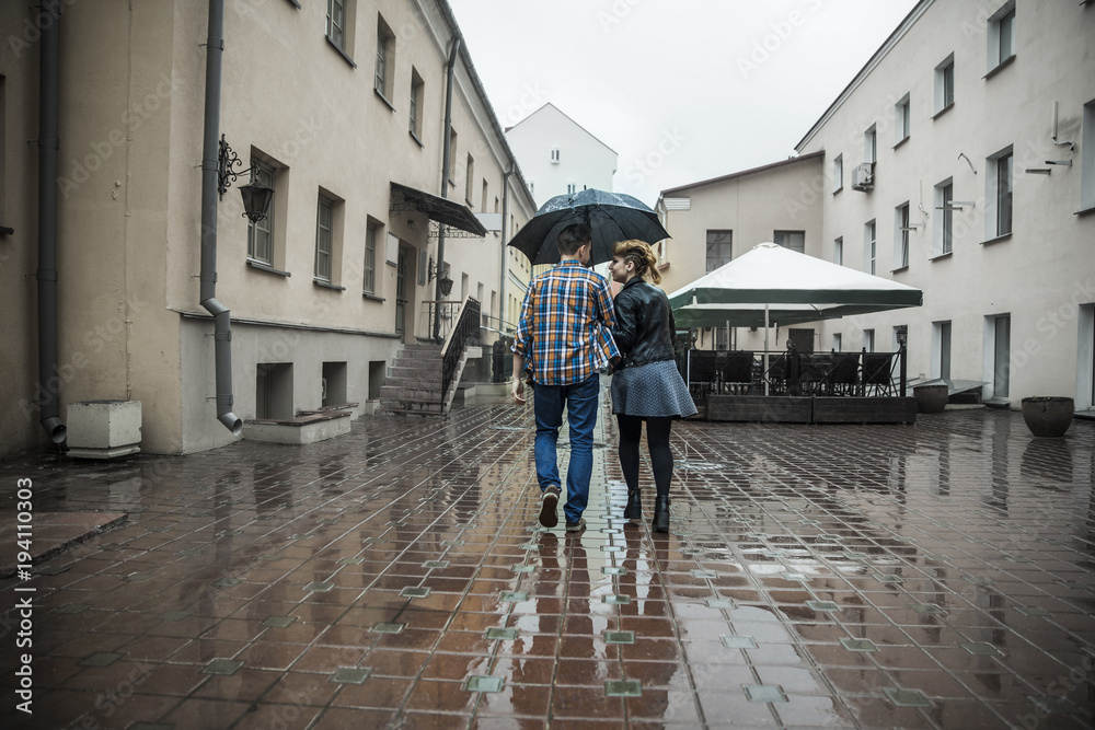 happy loving couple is under an umbrella on a city street on a rainy day