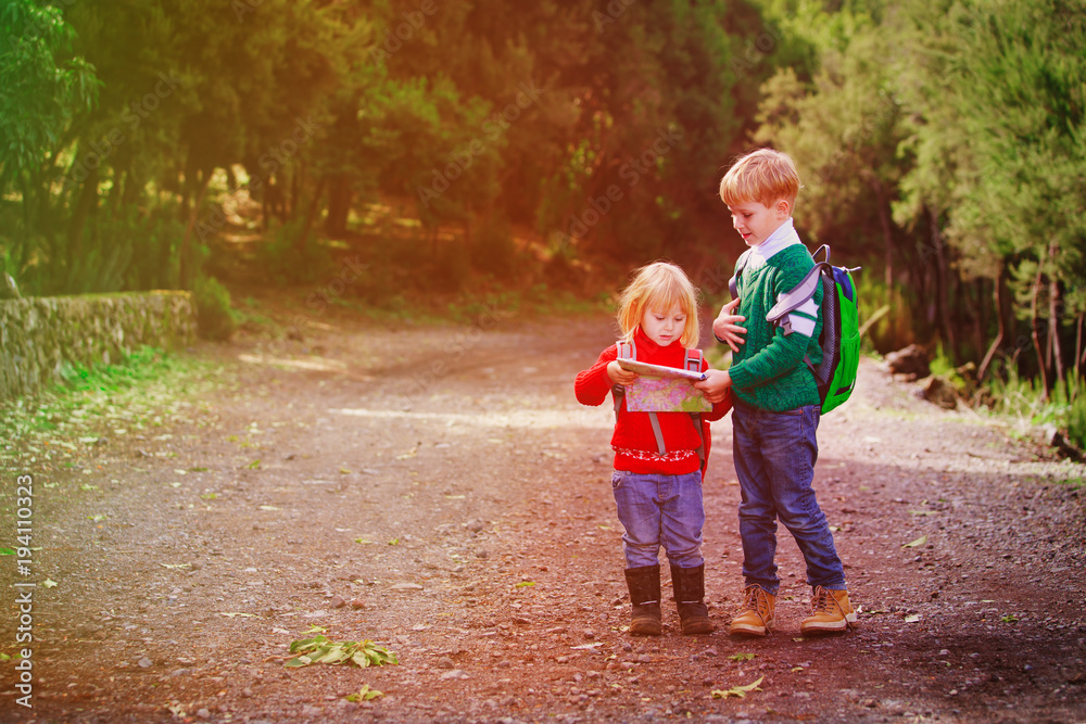 little boy and girl travel hiking in nature looking at map little boy and girl travel hiking in nature looking at map