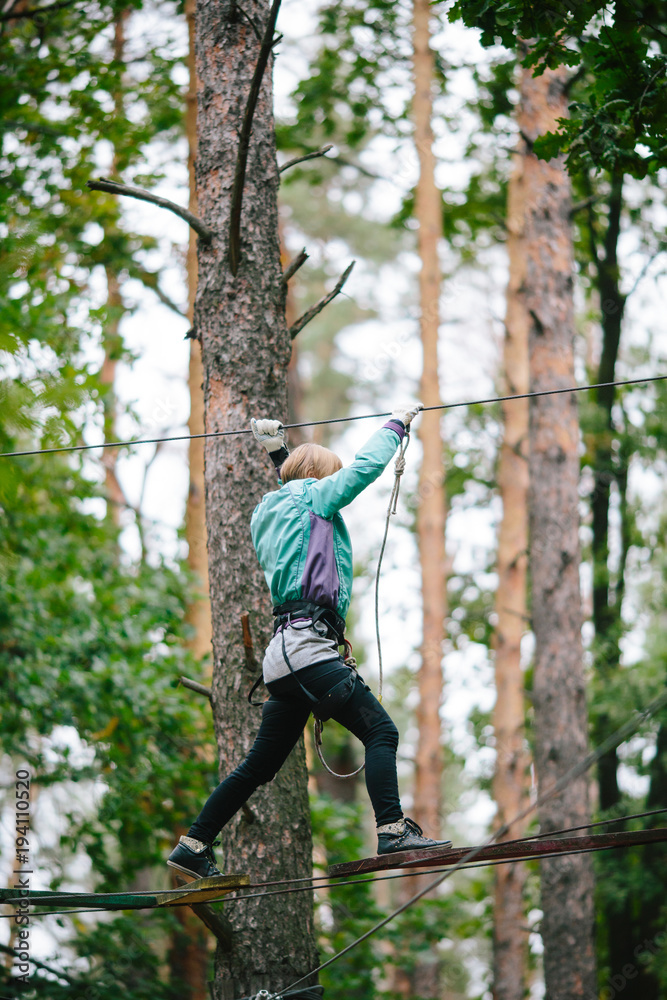 adventure climbing high wire park - woman on course in mountain helmet and safety equipment