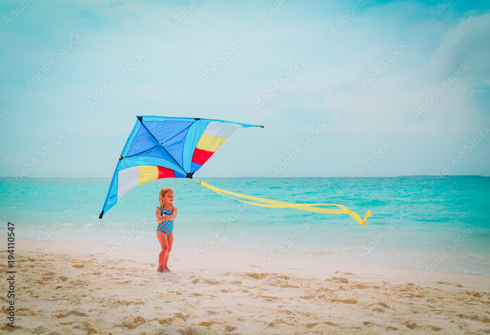 Happy cute little girl flying a kite on beach Stock Photo | Adobe Stock