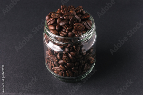 roasted coffee beans in a glass jar  on a gray background