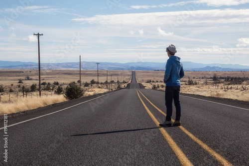 Man is standing in the middle of the long road during a vibrant sunny day. Taken in Oregon, North America. © edb3_16