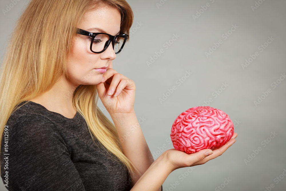 Woman thinking and holding fake brain Woman thinking and holding fake brain